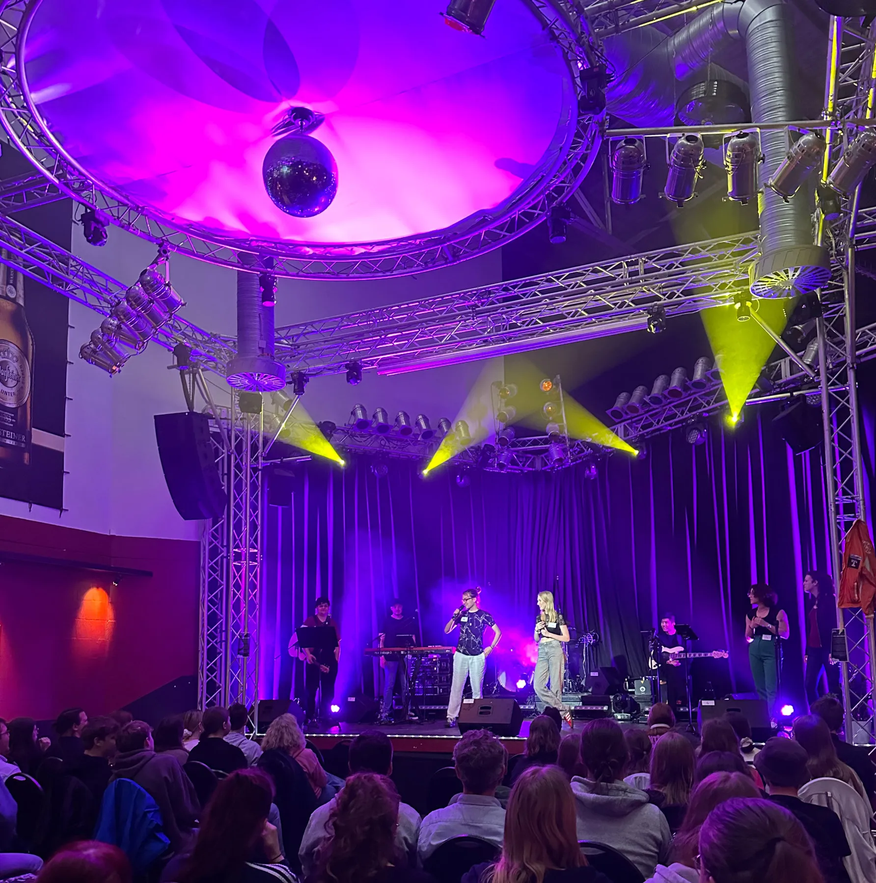 Die glow Band auf der Bühne in violettem Licht, davor das Publikum